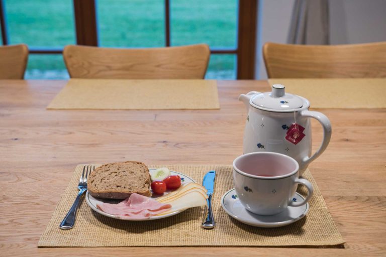 obložený talíř, příbor, šálek a konvice s čajem