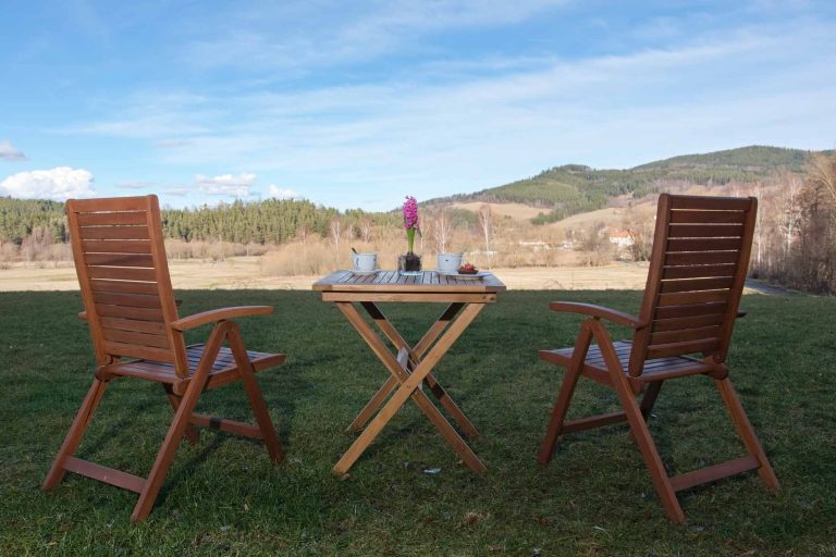 dvě dřevěné židle se stolem s občerstvením, výhled do krajiny