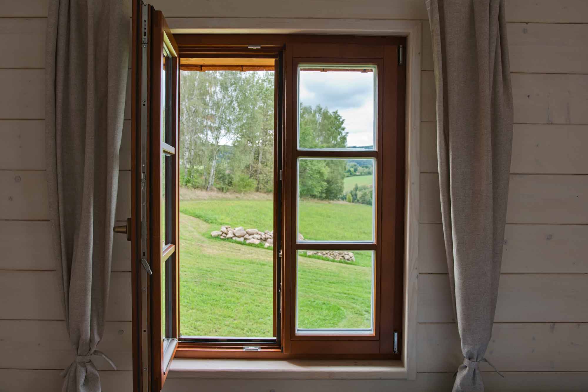 otevřené dřevěné okno s výhledem na zelené louky